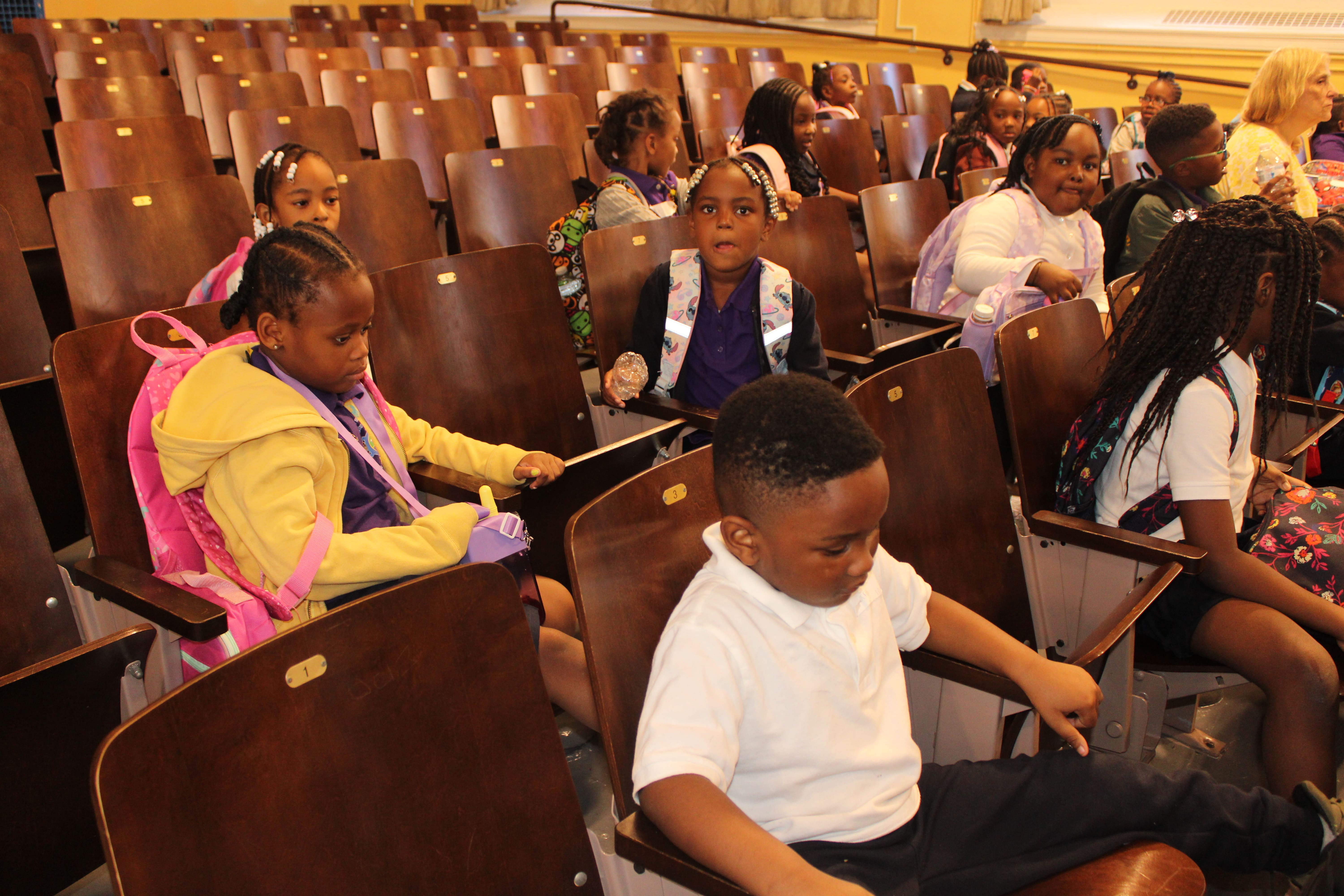 Five children standing on a polished gym floor 