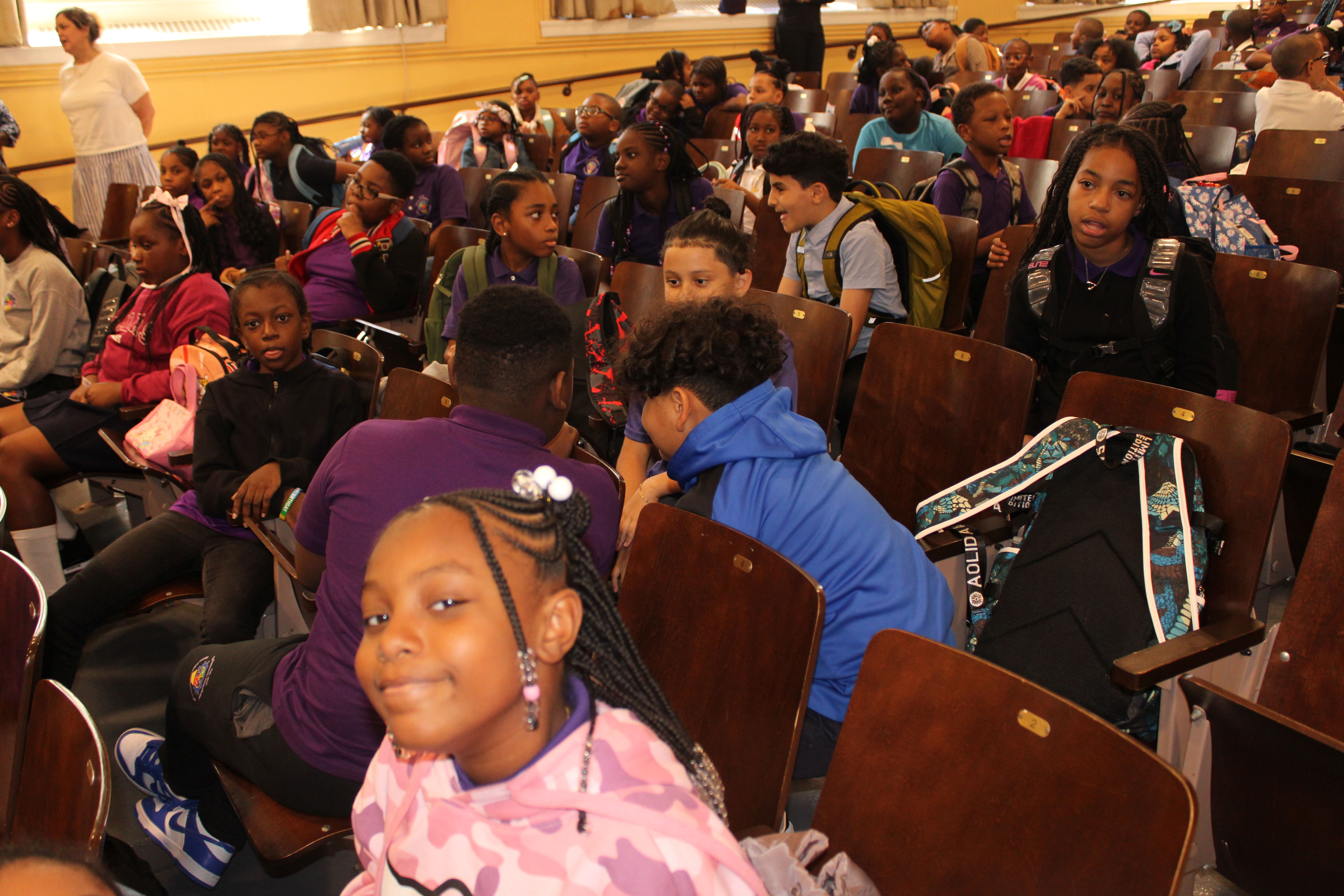 Five children standing on a polished gym floor 