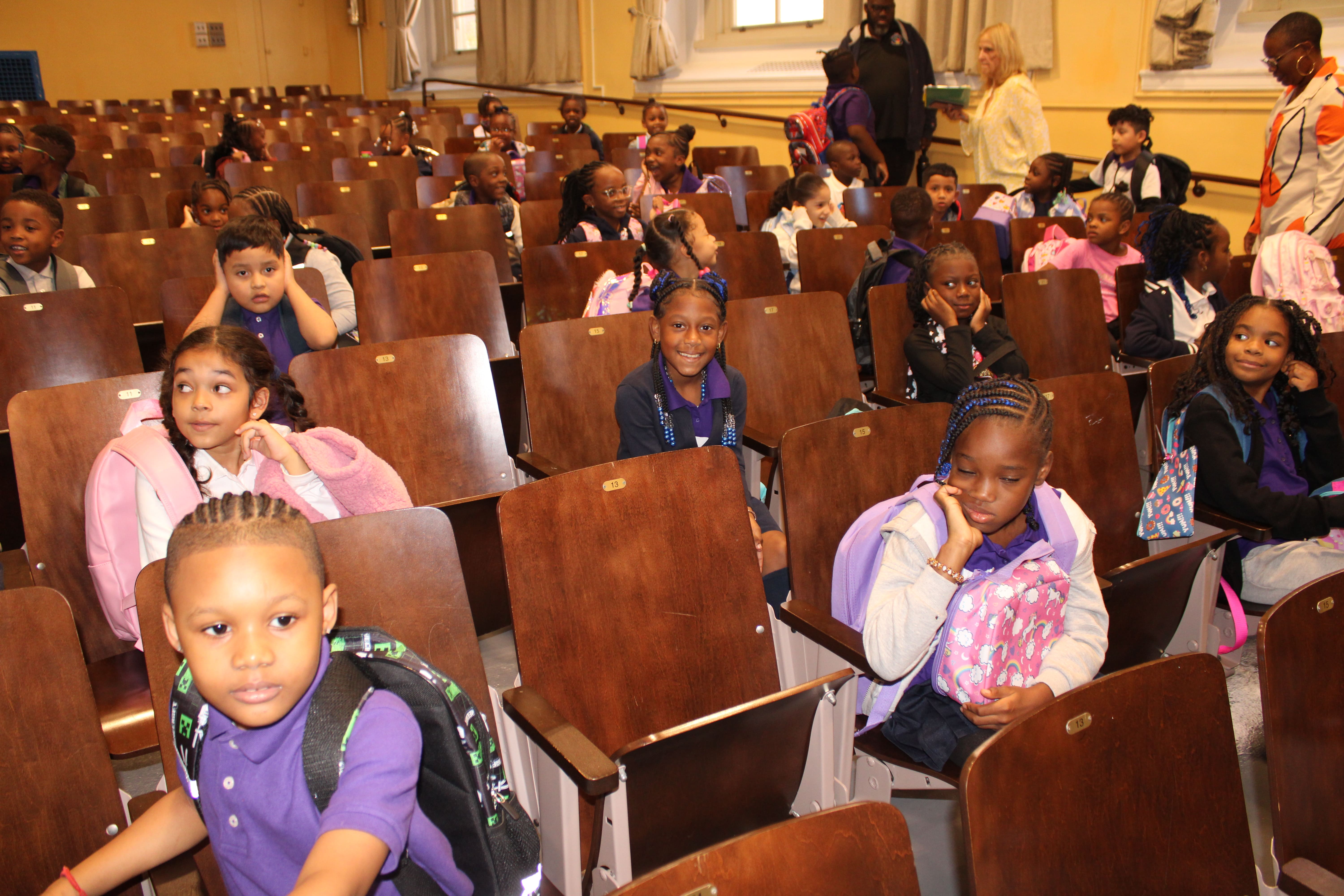 Five children standing on a polished gym floor 