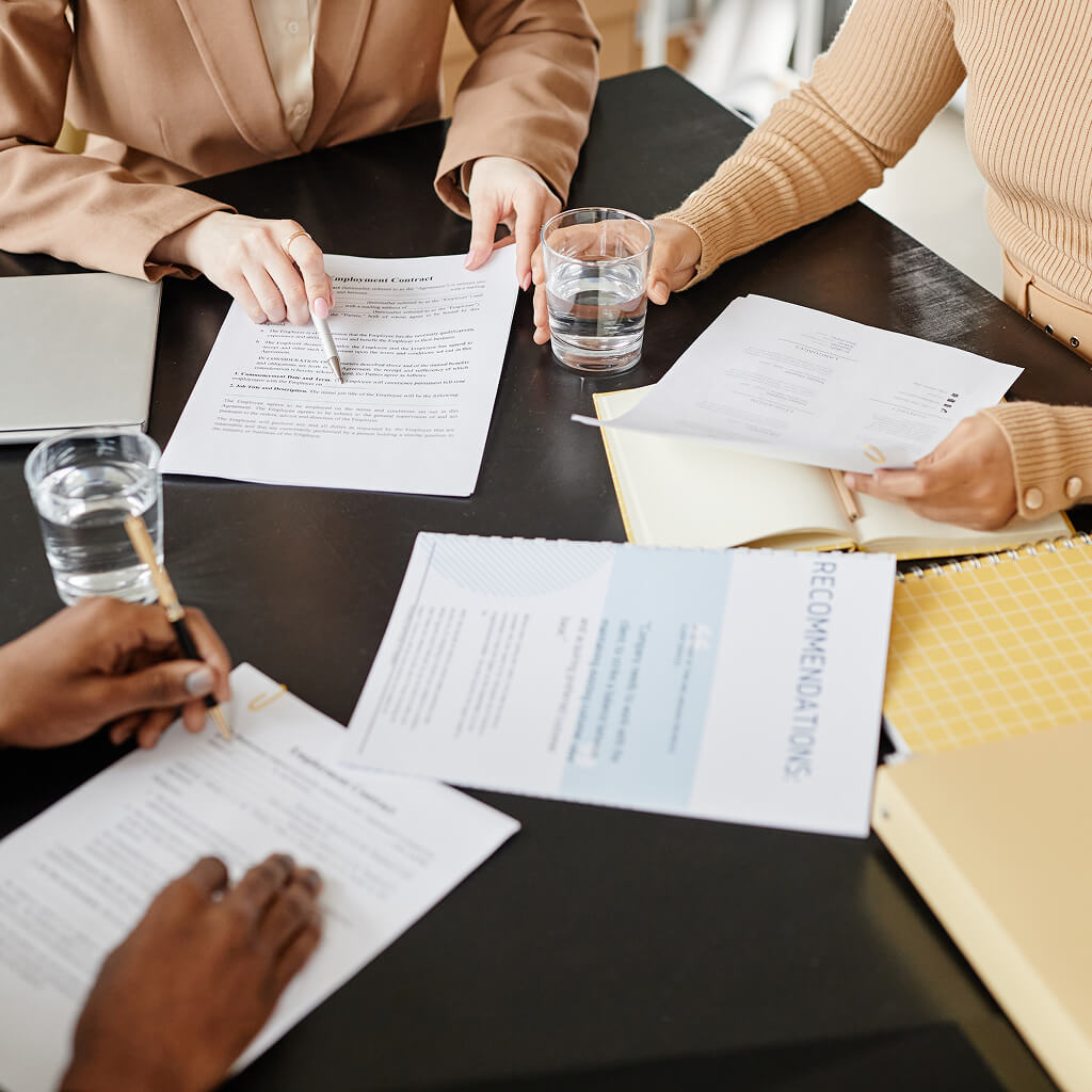 three people at a conference room table reviewing paperwork together