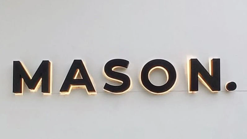 A lit dimensional-letter villa sign on a rendered entrance wall in Bali