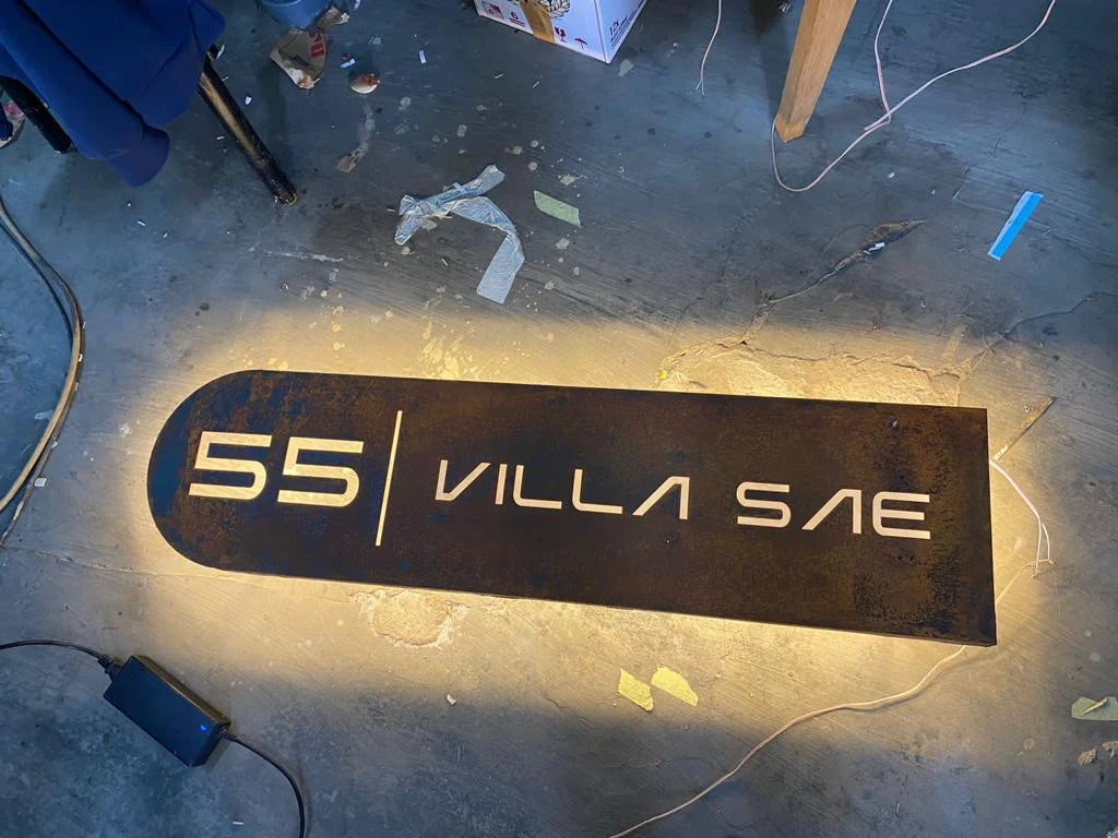 A solar-lit freestanding villa sign on a Bali lane after dark