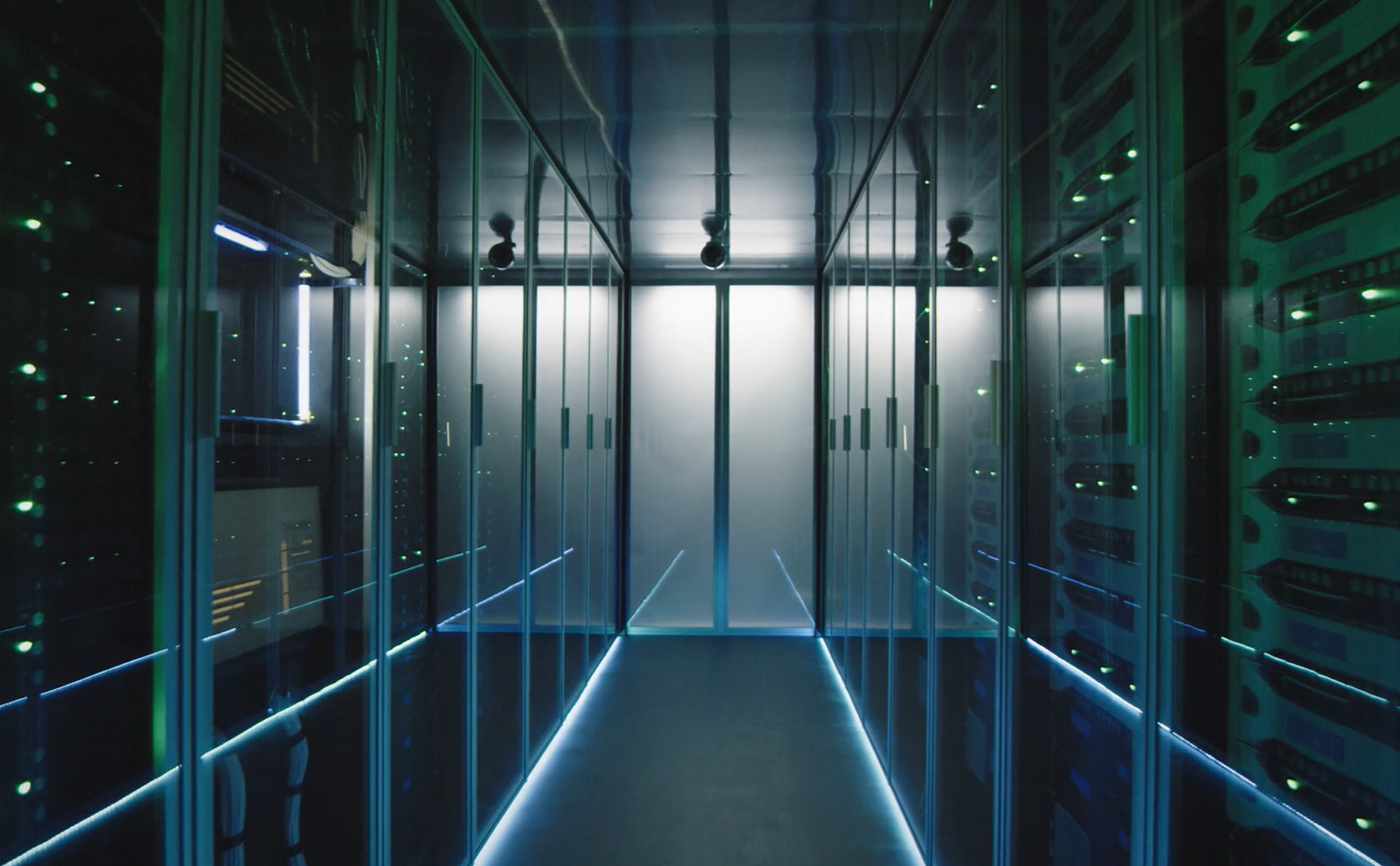 Corridor inside a data center with server racks on both sides illuminated by blue LED strips.