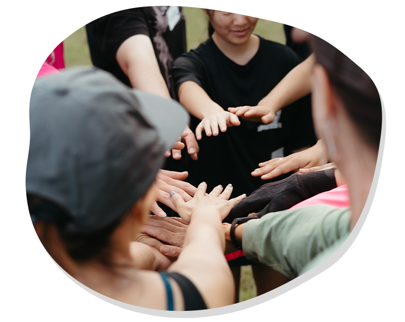 Group of people reaching their hands together in a team gesture outdoors.