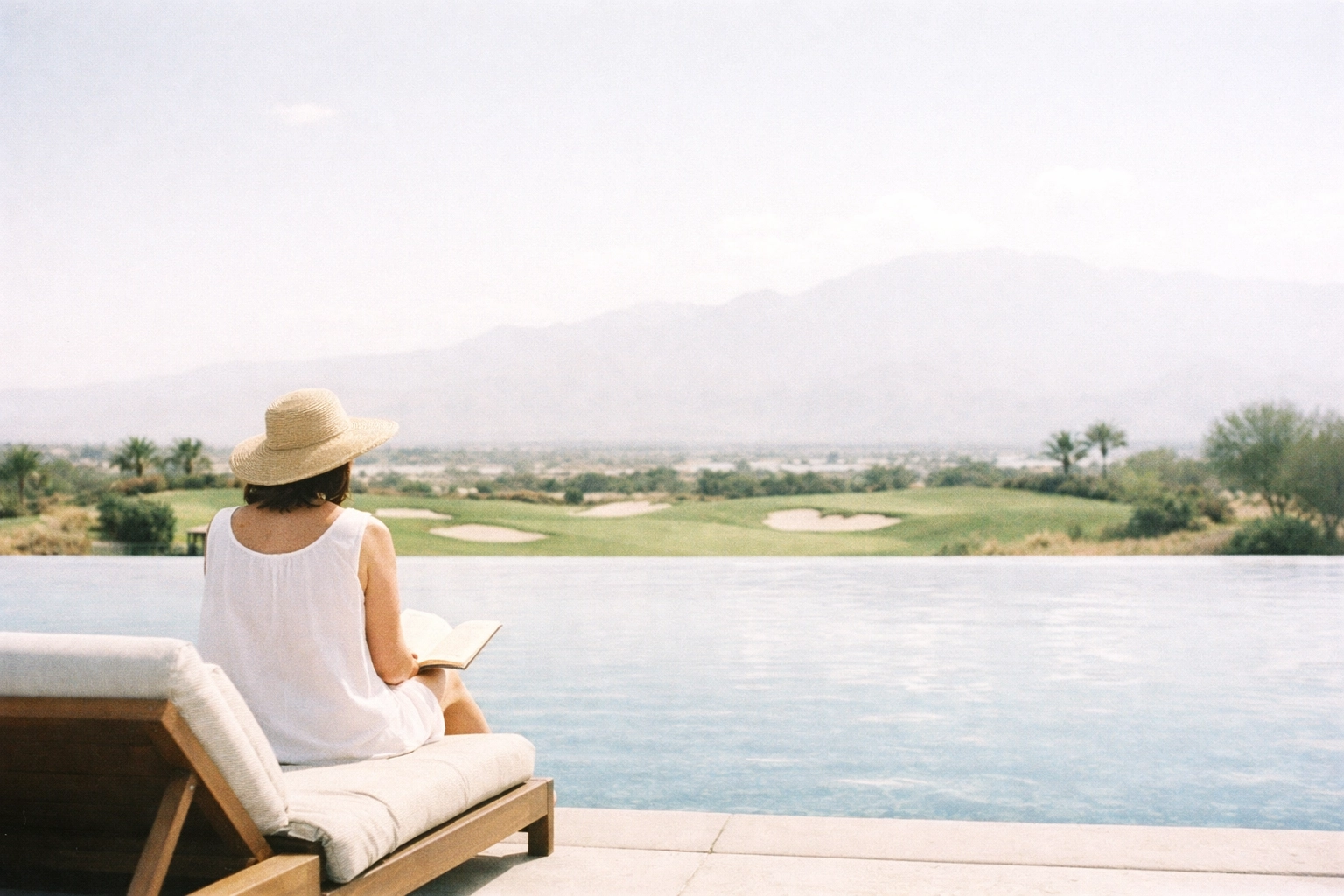 A non-golfer relaxing by a luxury resort infinity pool with views of a world-class golf course.