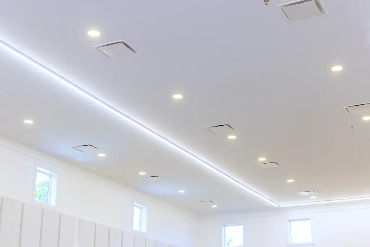 Clean white ceiling featuring evenly spaced round recessed ceiling lights.