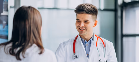 Male doctor smiling and talking with a woman in a medical office.