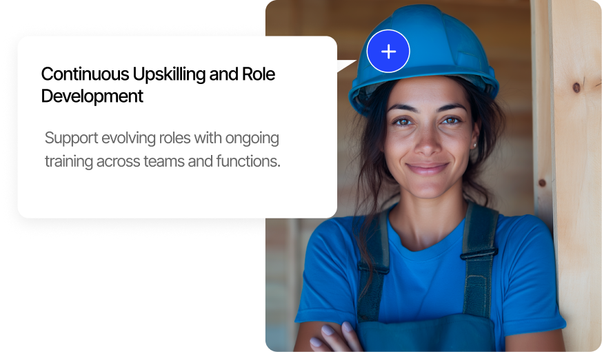 Smiling woman wearing a blue safety helmet and blue work shirt, standing with arms crossed beside a wooden beam.