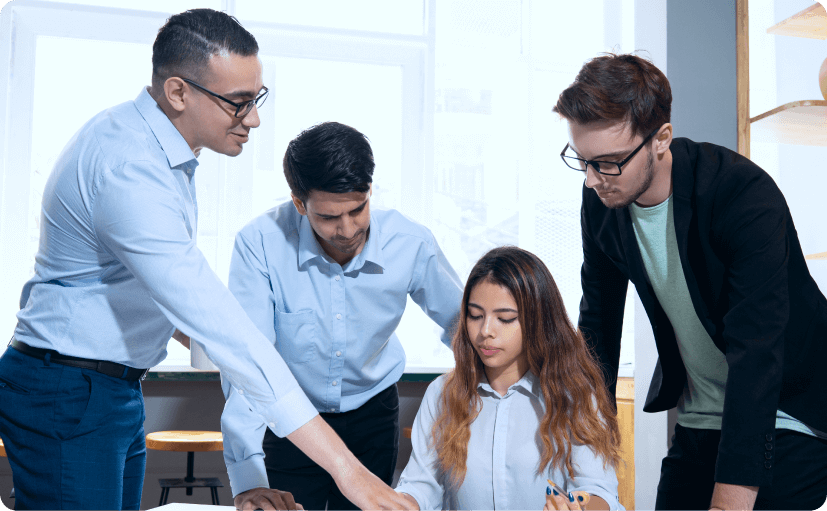 Four professionals collaborating and discussing work around a table in a bright office setting.