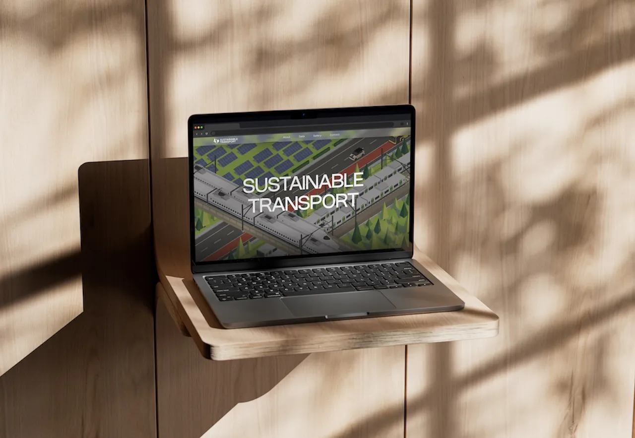 MacBook Pro displaying the 'Sustainable Transport' homepage design, featuring a detailed isometric illustration of electric trains and solar farms.