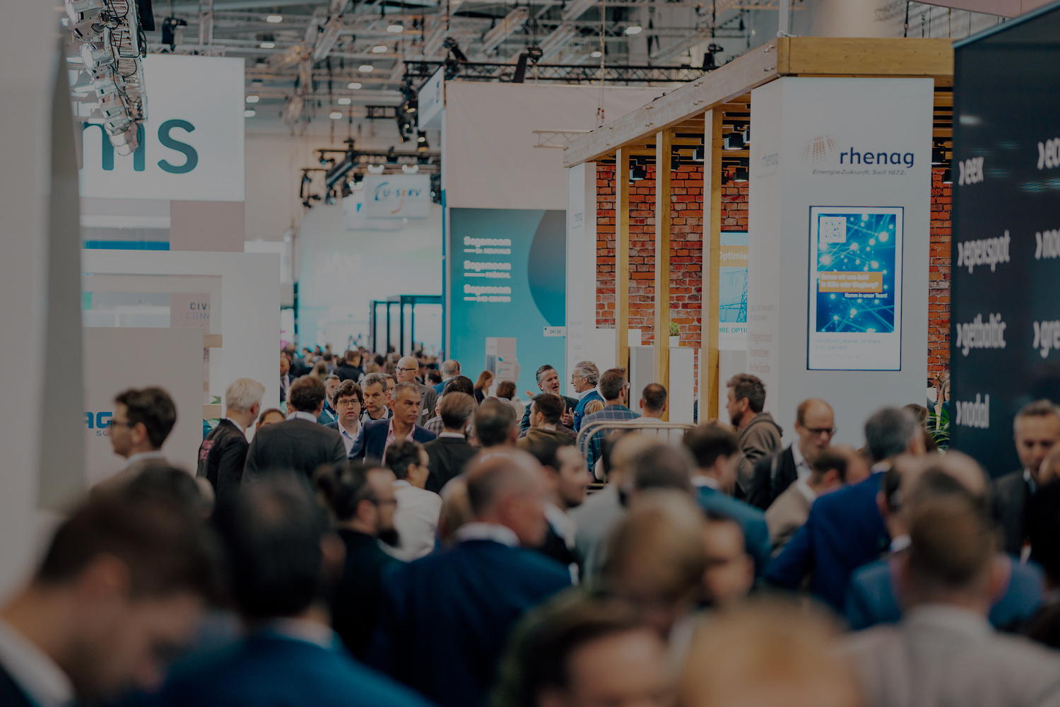 Menschenmenge auf einer Messe oder Konferenz mit Messeständen und Informationsdisplays.