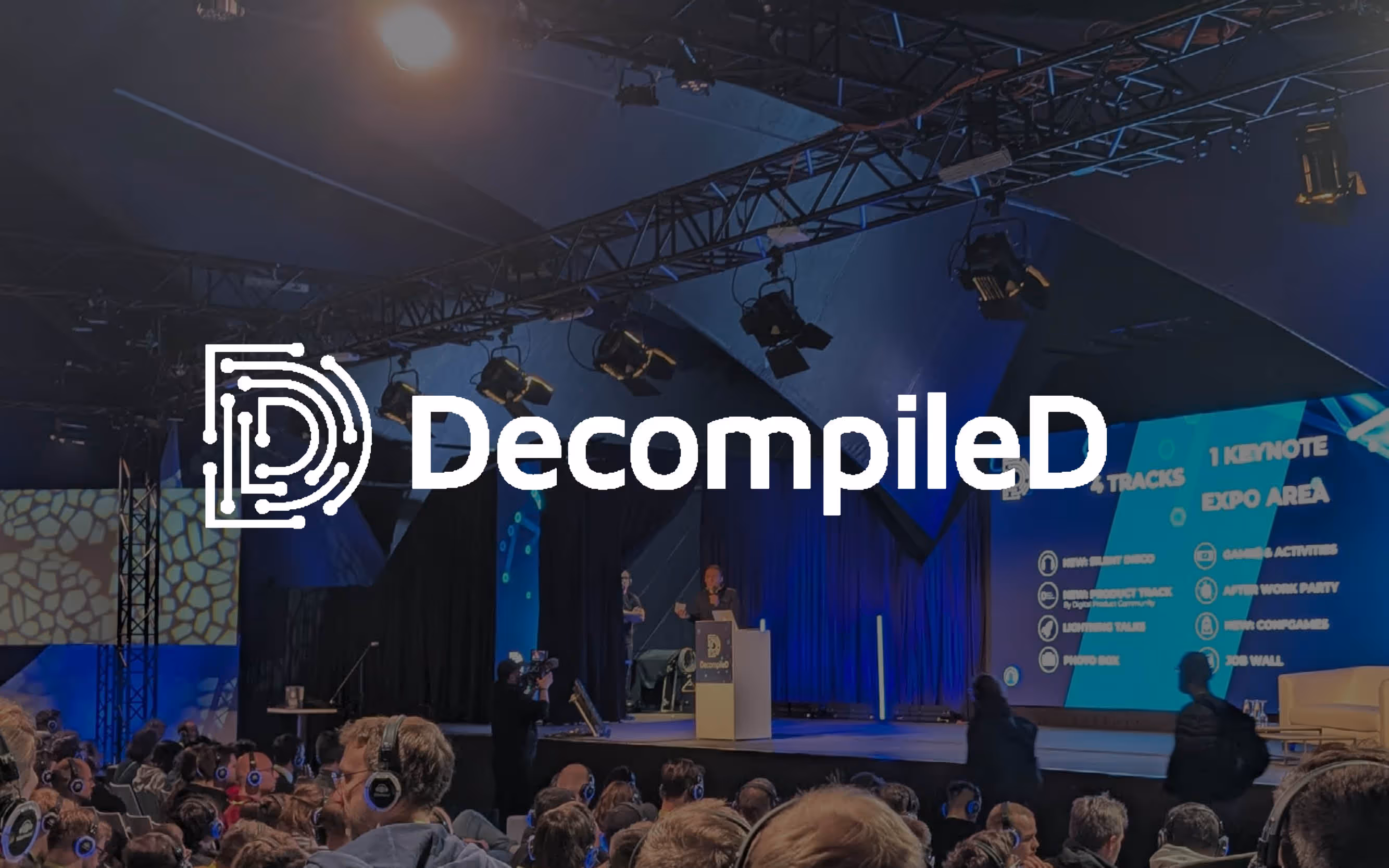 Volles Publikum mit Kopfhörern bei einer Präsentation auf der DecompileD-Konferenzbühne.