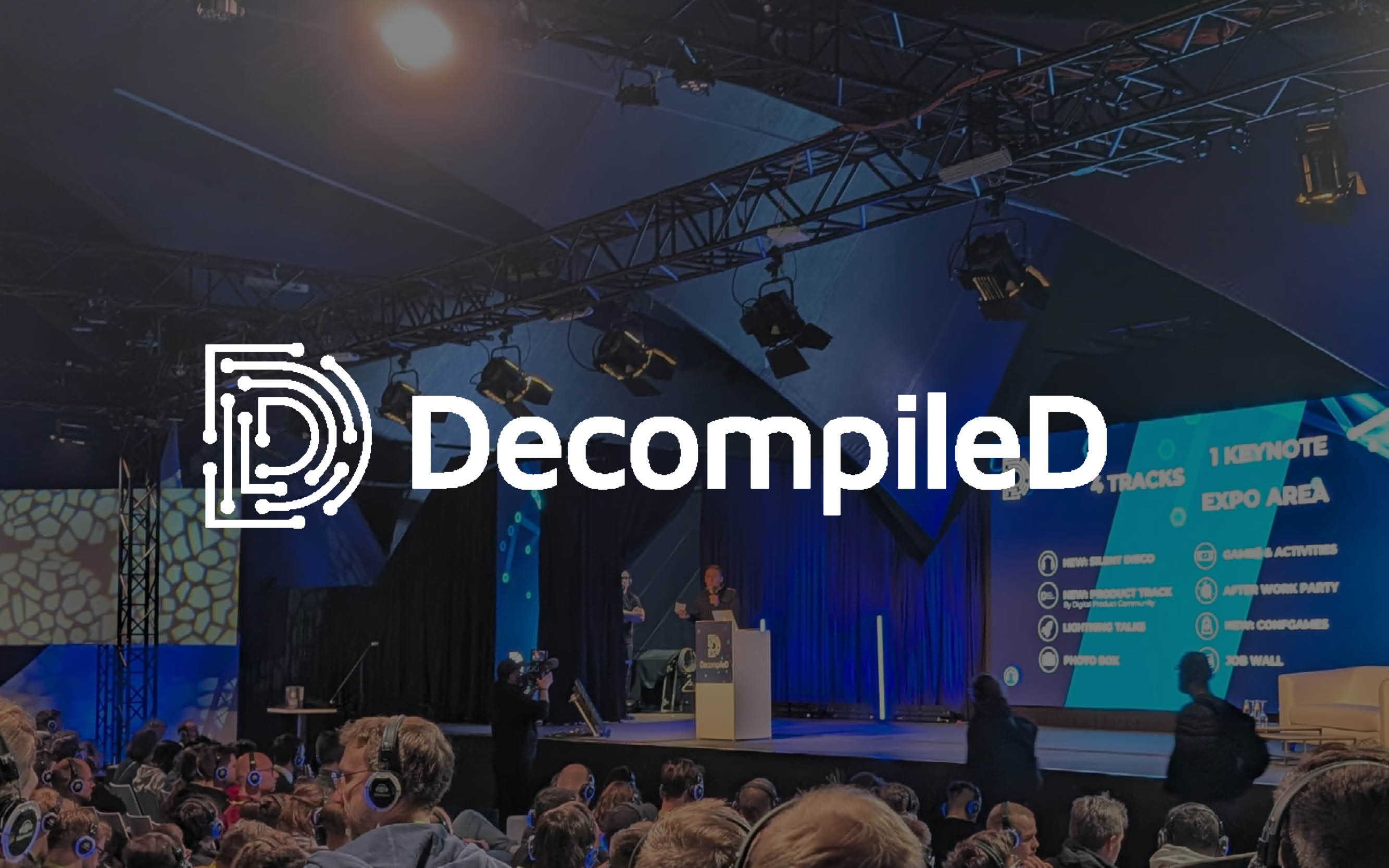 Volles Publikum mit Kopfhörern bei einer Präsentation auf der DecompileD-Konferenzbühne.