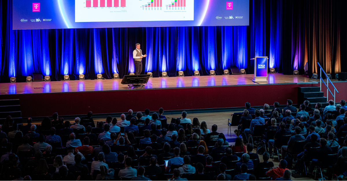 Volles Publikum mit Kopfhörern bei einer Präsentation auf der DecompileD-Konferenzbühne.