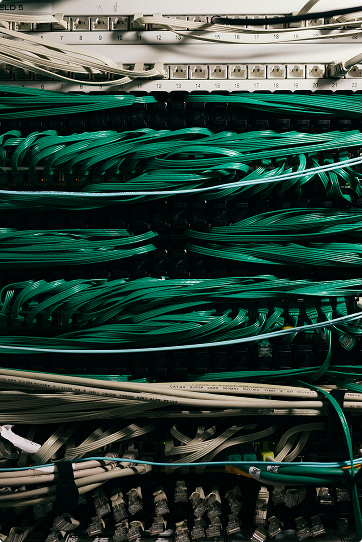 Close-up of an organized network server rack with bundled green and white Ethernet cables connected to patch panels.