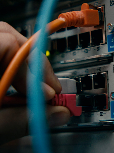 Network server equipment with multiple Ethernet ports behind a black hexagonal mesh panel and yellow cables on the left.