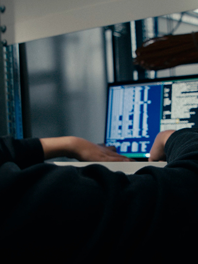 Server rack with router behind a mesh cage with yellow and blue cables.