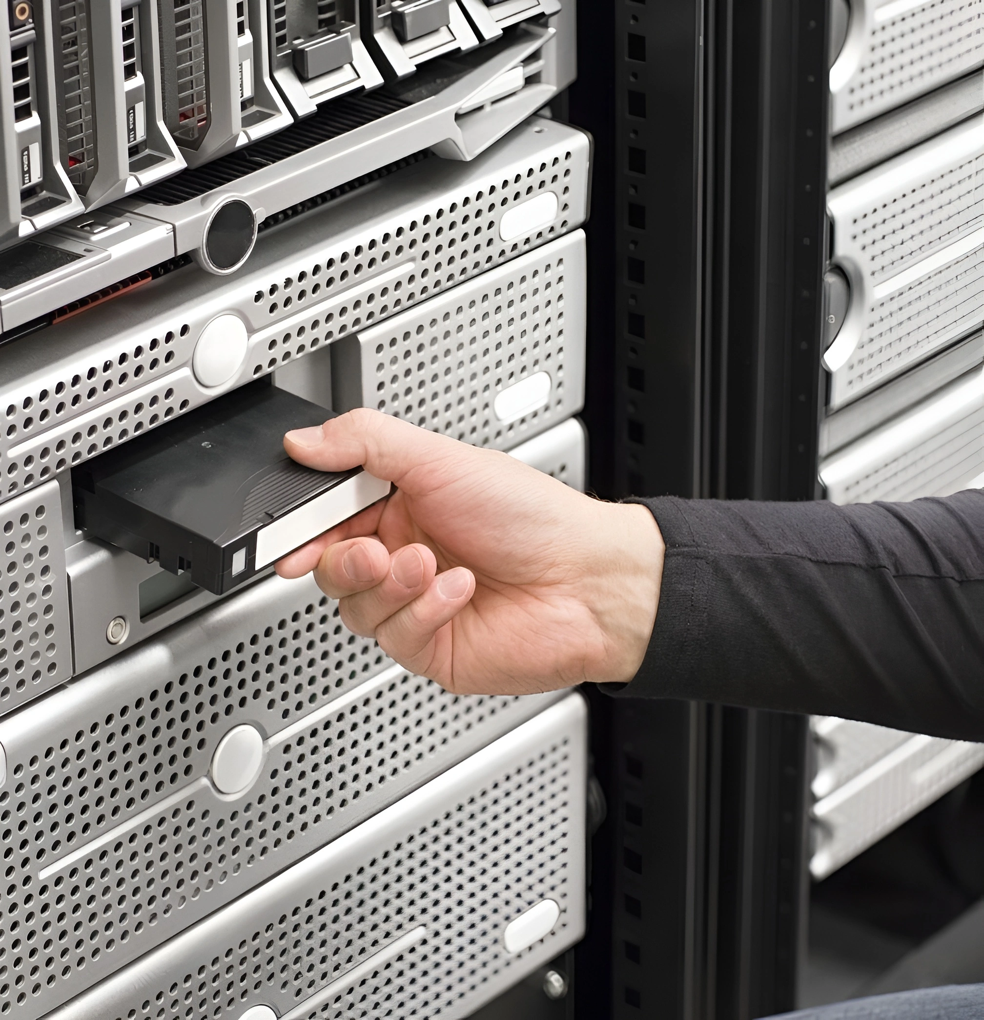 Hand entfernt eine Festplatte aus einem Server-Rack in einem Rechenzentrum.