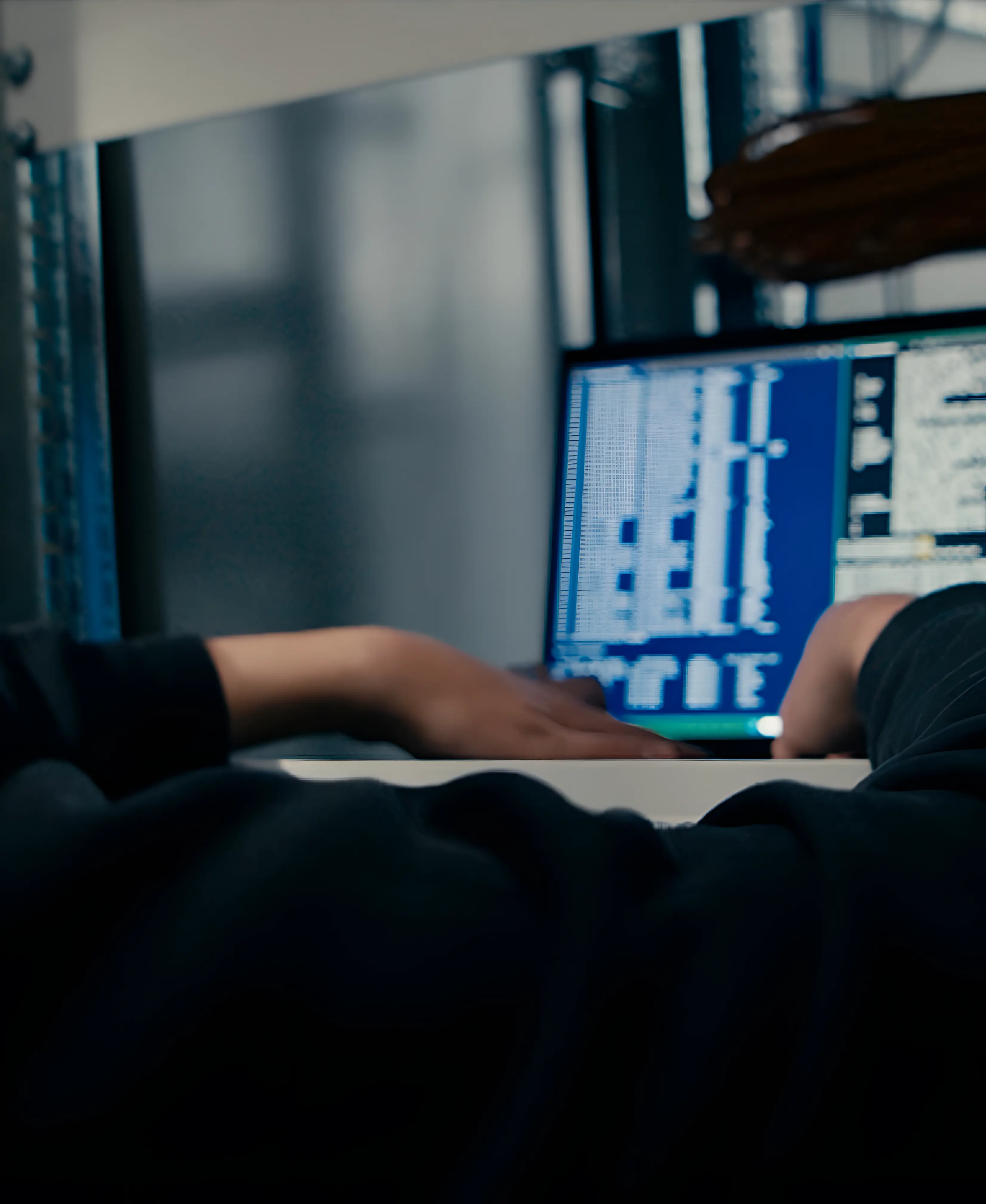 Person, vermutlich ein Programmierer, arbeitet an einem Computer mit Code auf dem Bildschirm.
