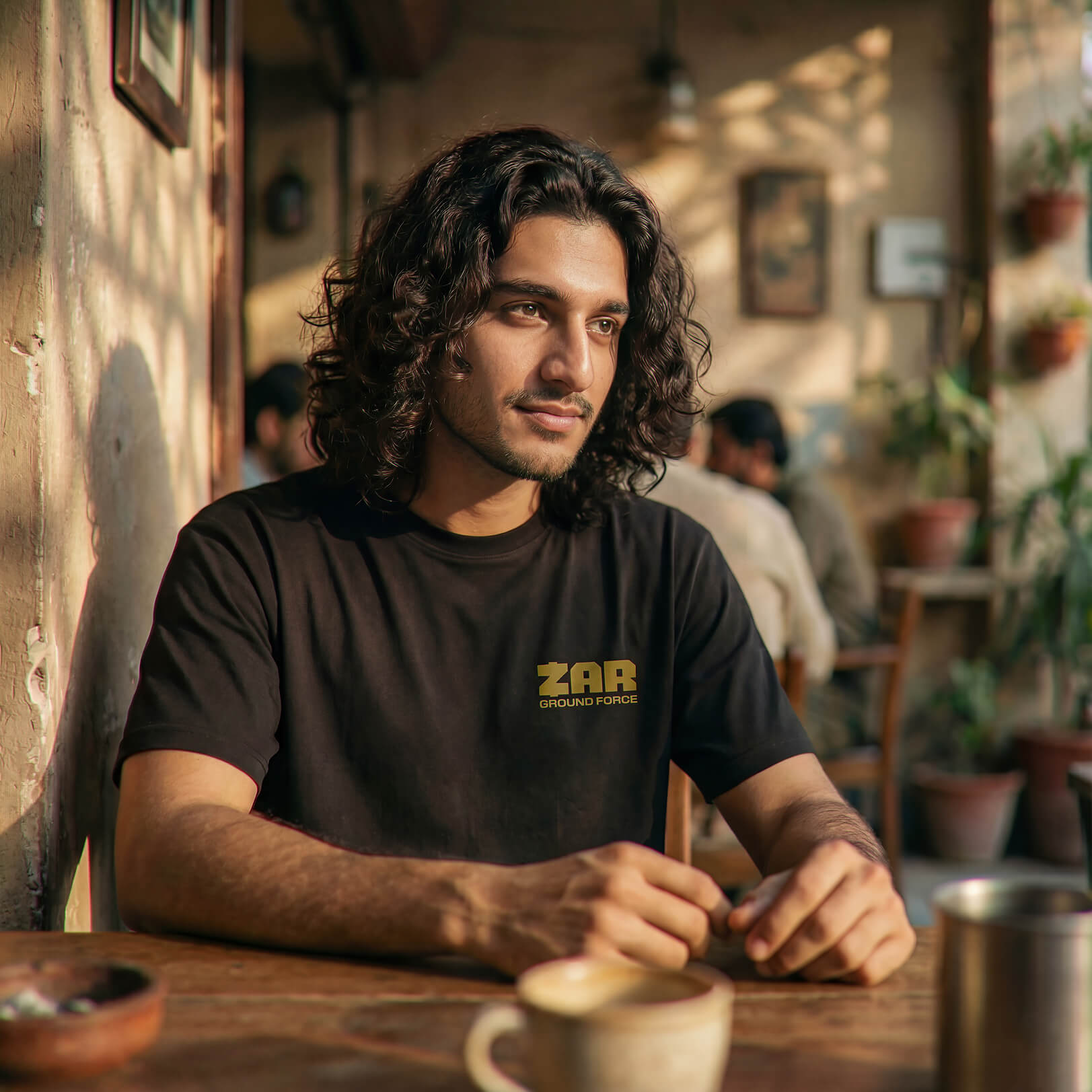 a man wearing a zar shirt in a coffee shop