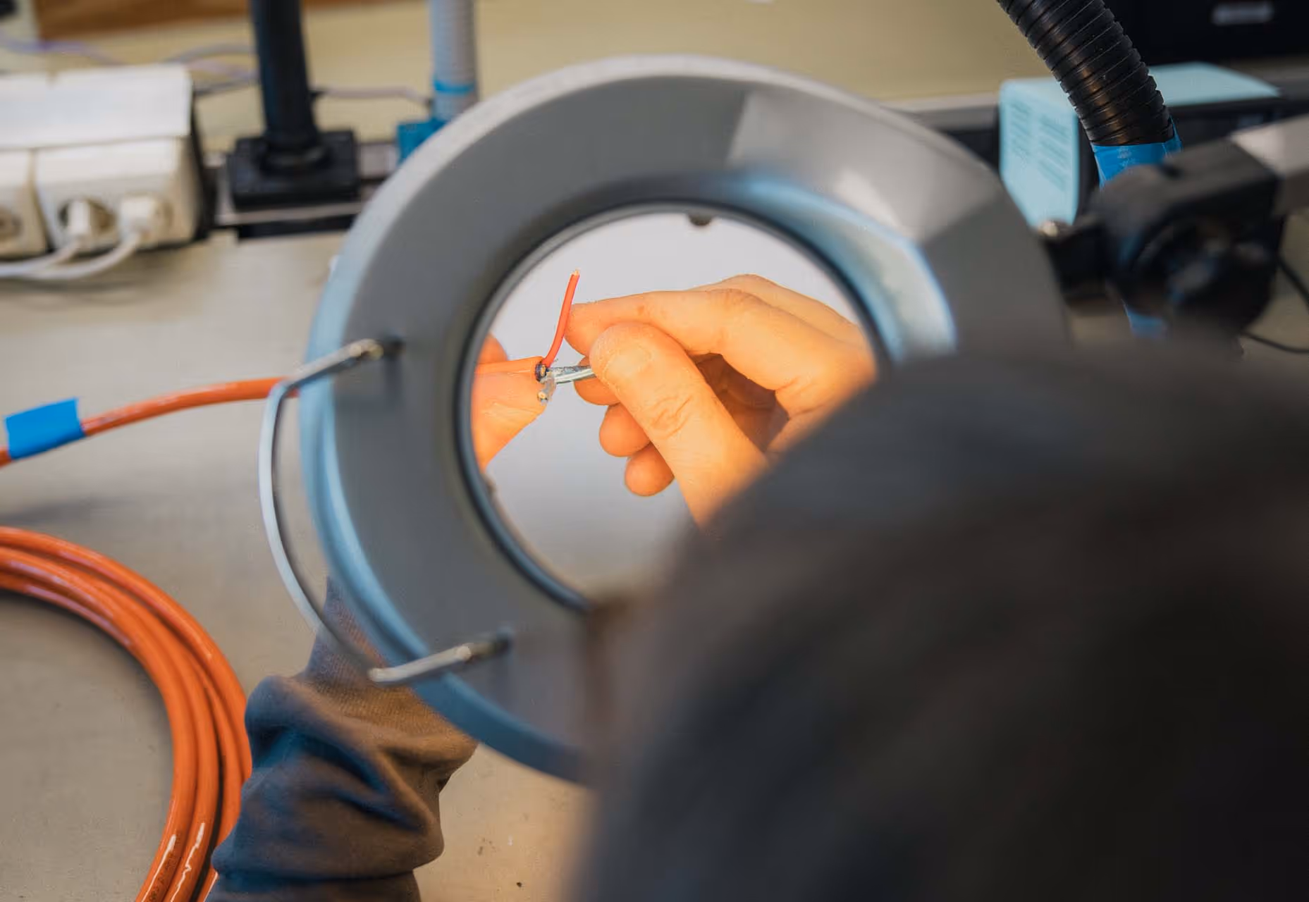 En person bruker et forstørrelsesglass for å jobbe med en liten elektrisk ledning.