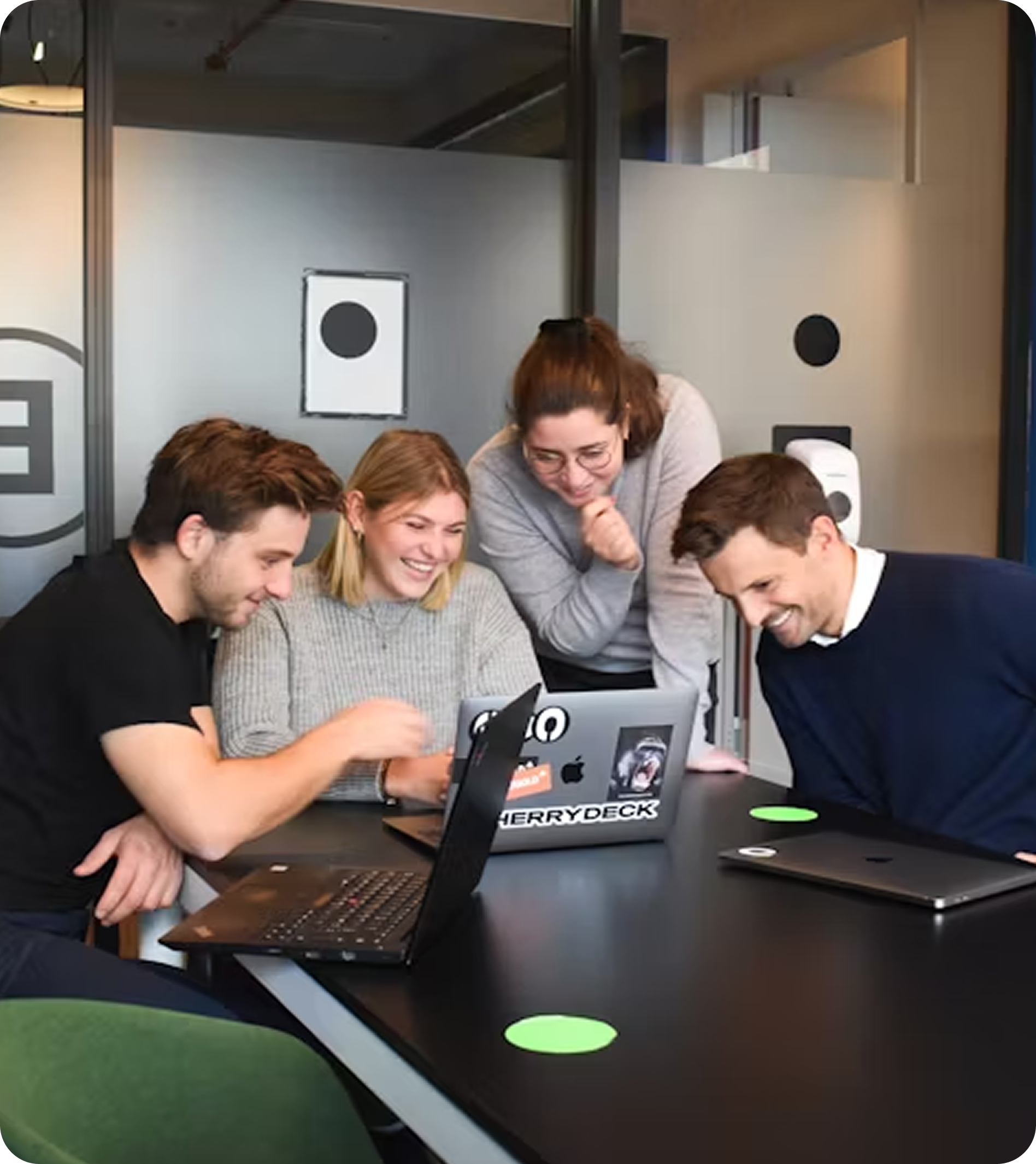 A group of people sitting around a table with laptops.