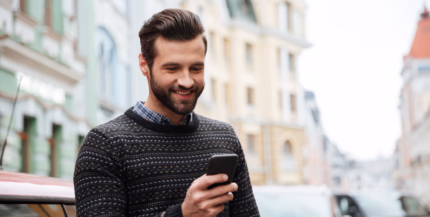 A man smiling while using his smartphone to contact ONE Power Fitness support.