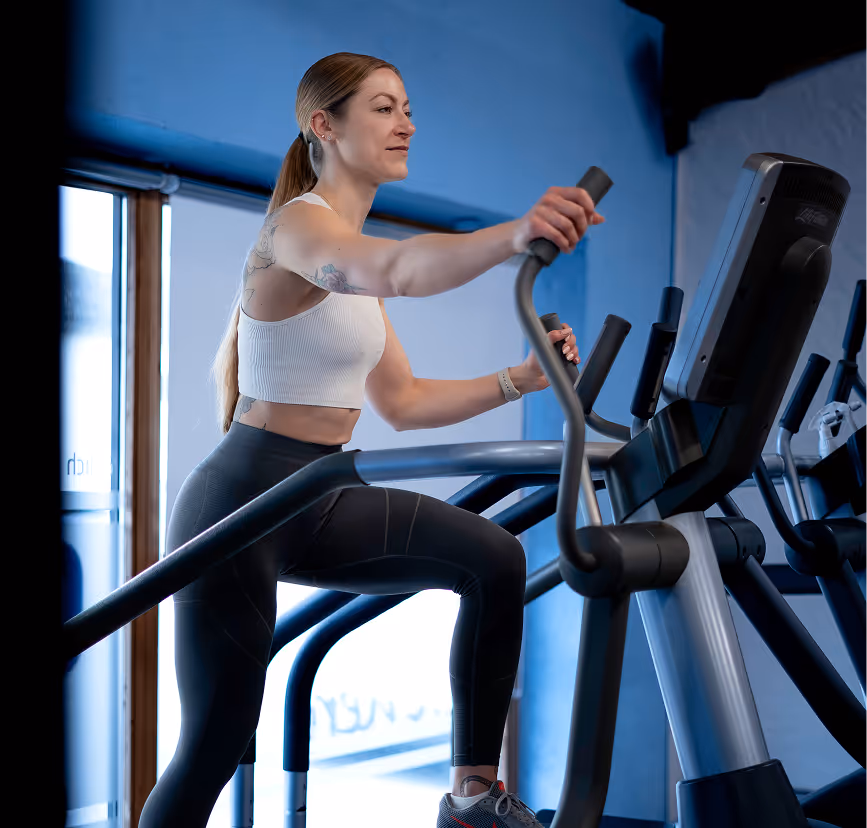 Woman training on cardio machine in a bright, modern 24/7 gym