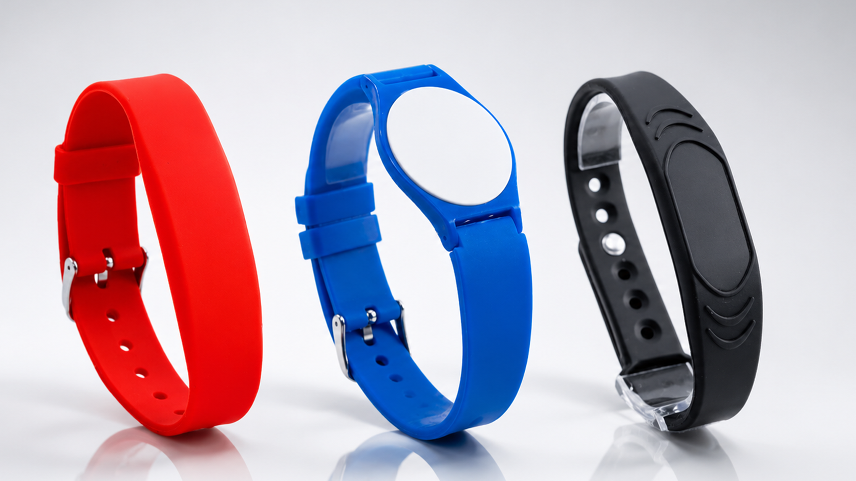 Drei Silikonarmbänder in Rot, Blau und Schwarz, auf weißem Hintergrund.