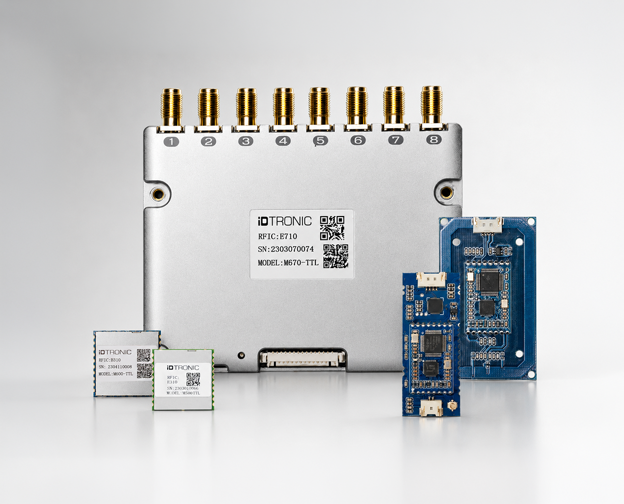 RFID-Gerät mit acht goldenen Anschlussporten und drei kleinen elektronischen Modulen auf grauem Hintergrund.