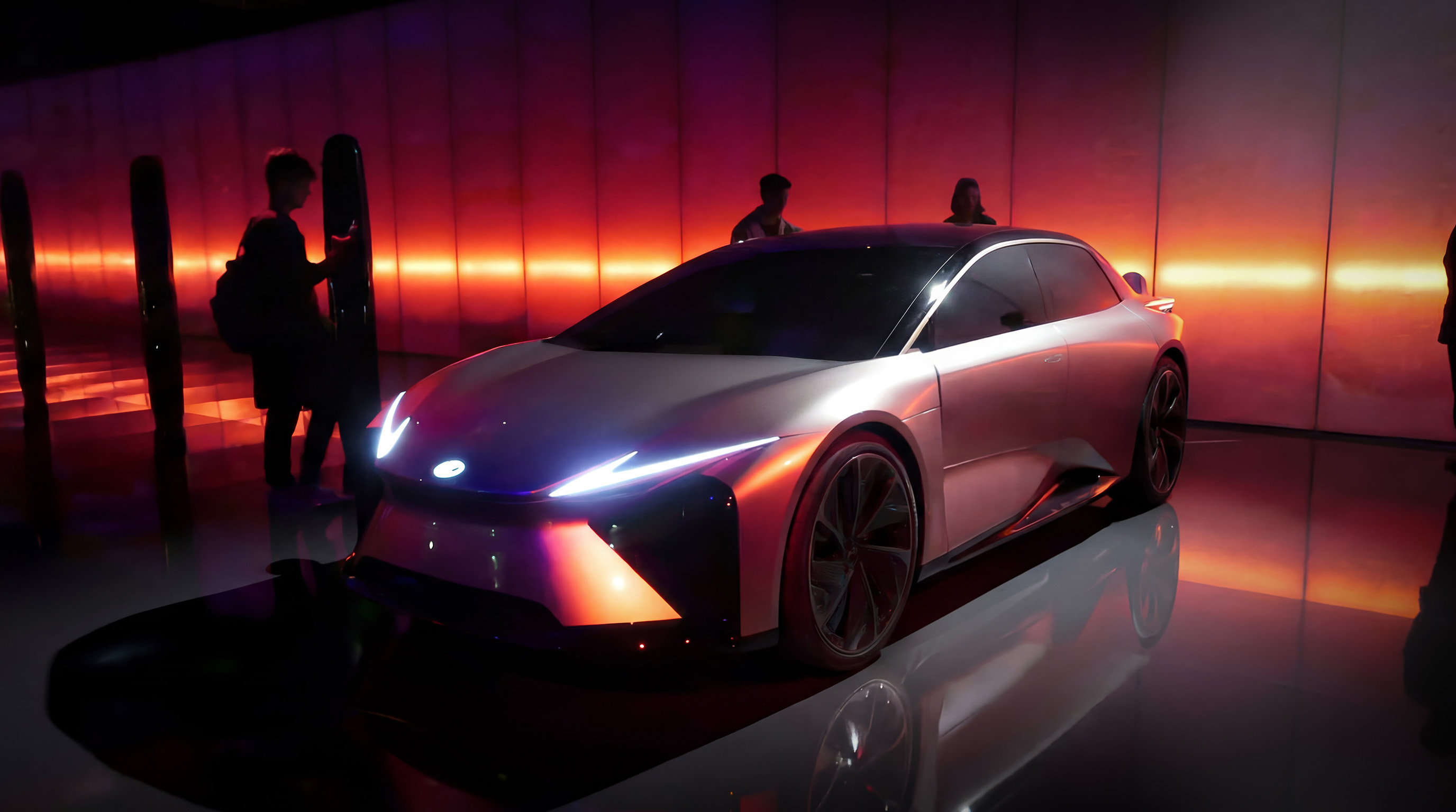 Stessa installazione Lexus, parete semitrasparente illuminata di rosso con luce tipo tramonto e visitatori presenti