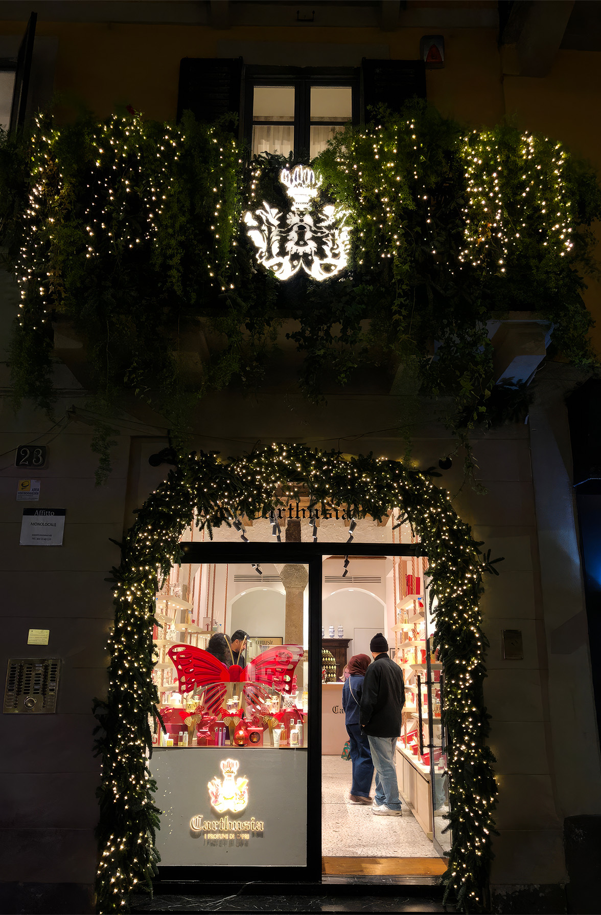 Negozio Carthusia visto da fuori di sera, illuminazione calda con atmosfera da luci natalizie