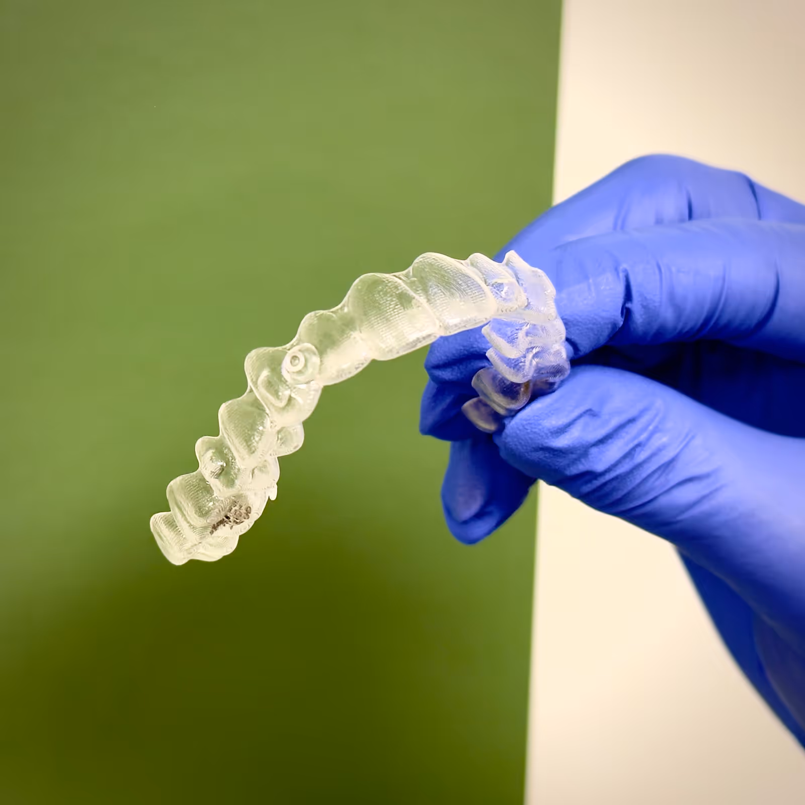 Dentist in purple scrubs showing a patient an X-ray of teeth on a monitor in a dental office.