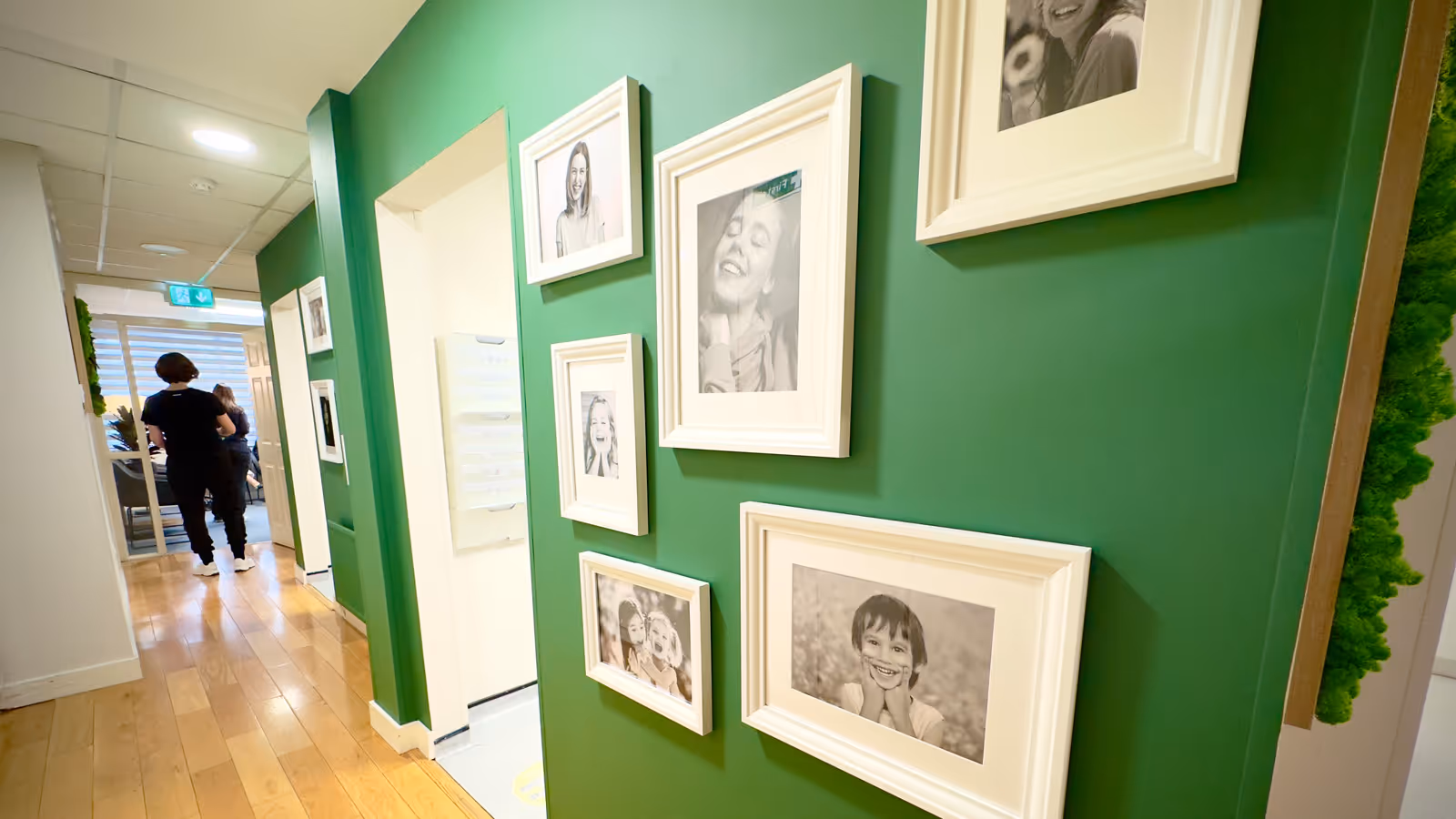 Dentist pointing at a dental X-ray on a screen while discussing it with a patient seated in a dental chair.