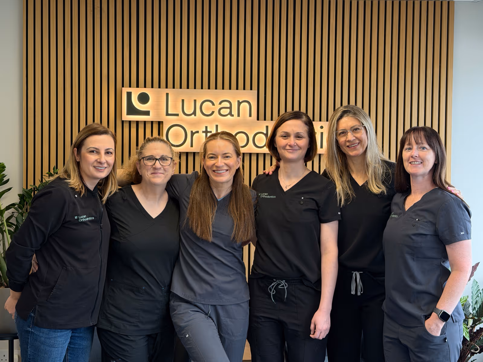 Dentist pointing at a dental X-ray on a screen while discussing it with a patient seated in a dental chair.