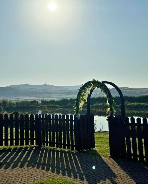 Rustic wedding arch with floral decorations at Sunset Lakes venue