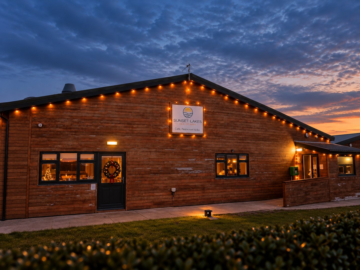 Sunset Lakes venue at dusk with lights glowing along the wooden building