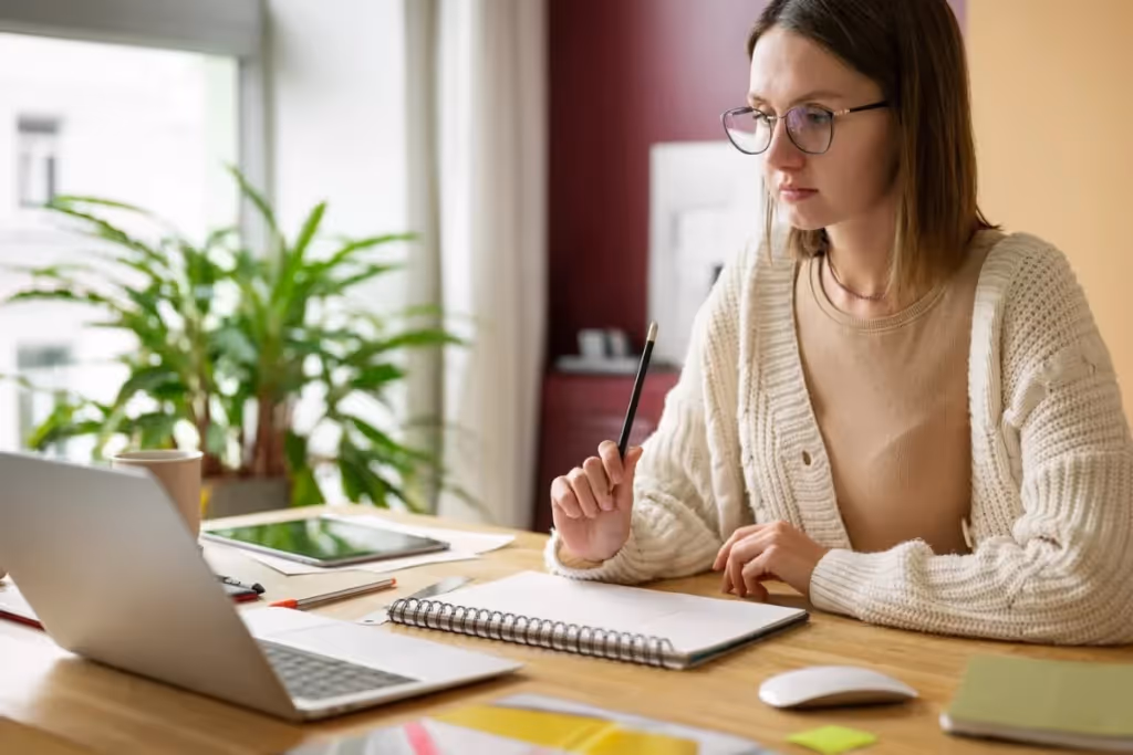 A person in glasses sitting at a desk with a laptop.