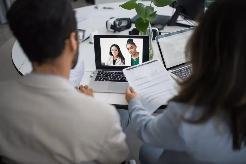 Two business professionals in a video conference call, discussing documents during a meeting.