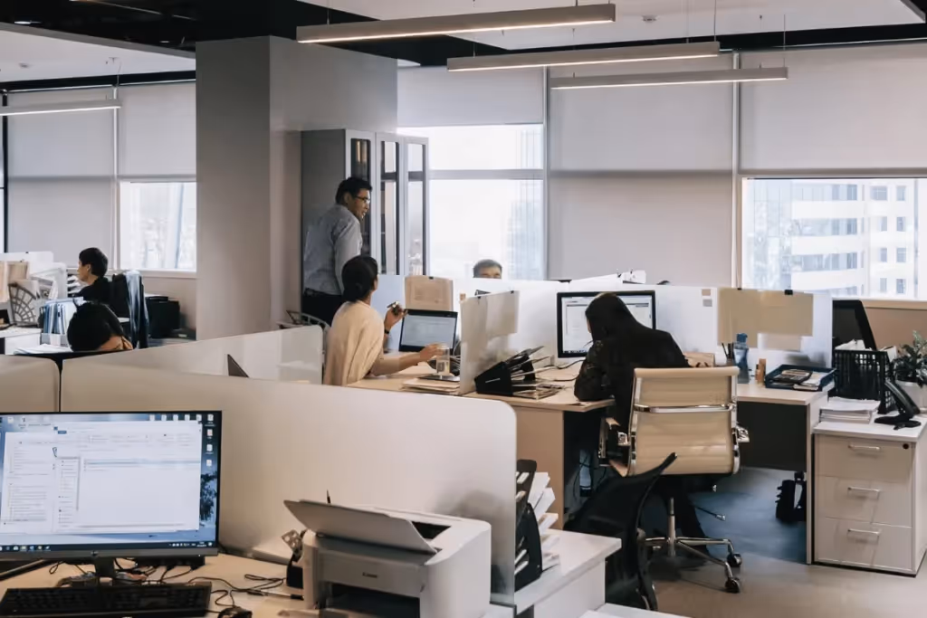 Open office with employees working at desks, using computers and collaborating.