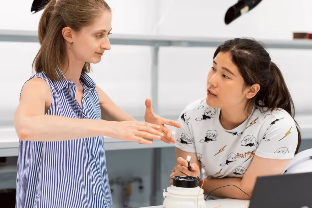 A woman explaining something to another woman in a lab.