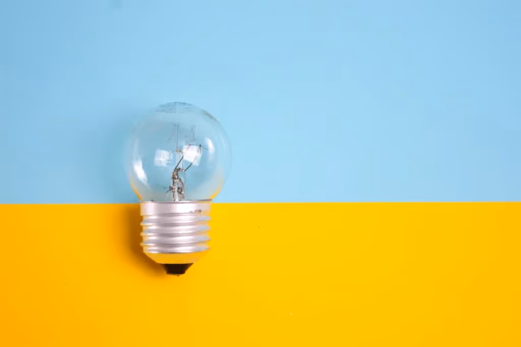 Clear light bulb resting on a bright blue and yellow background, representing innovation.