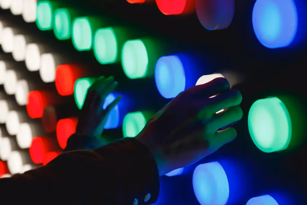 Close-up of hands interacting with a colorful LED light wall.