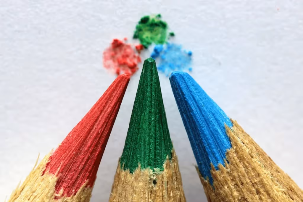 Close-up of red, green, and blue pencil tips with color smudges on a white background.