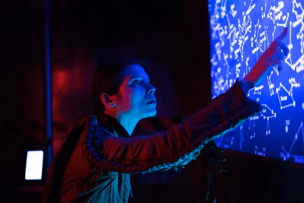 Person pointing at a digital constellation display with intense blue lighting.