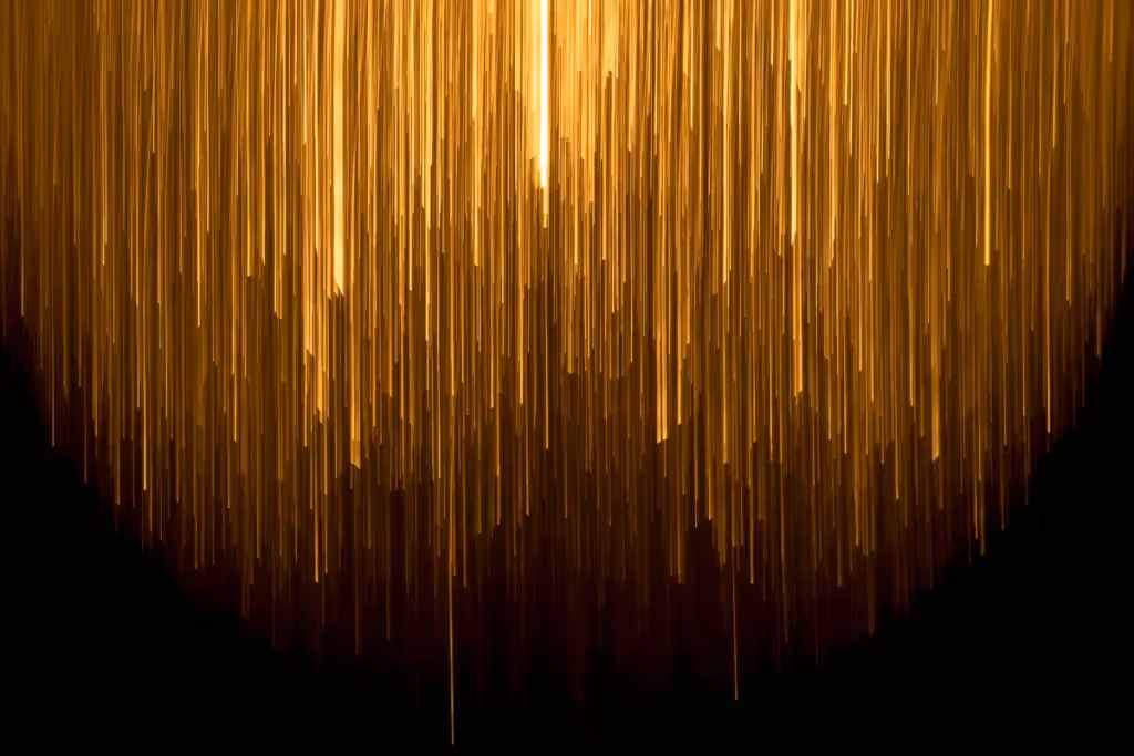 Golden light streaks cascading downward on a black background, creating a radiant abstract effect.