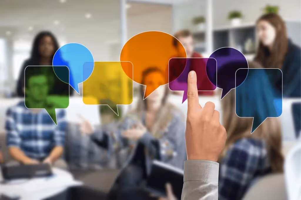 A person's hand pointing at colorful speech bubbles over a blurred office background.