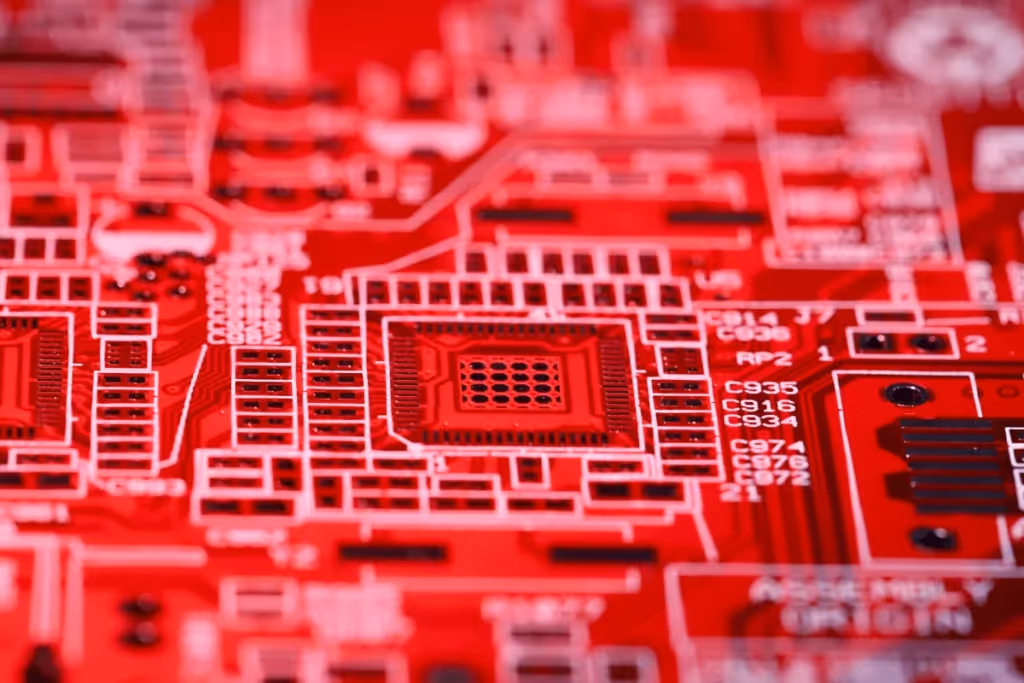 A vivid close-up of a red circuit board showcasing intricate electronic pathways and components.