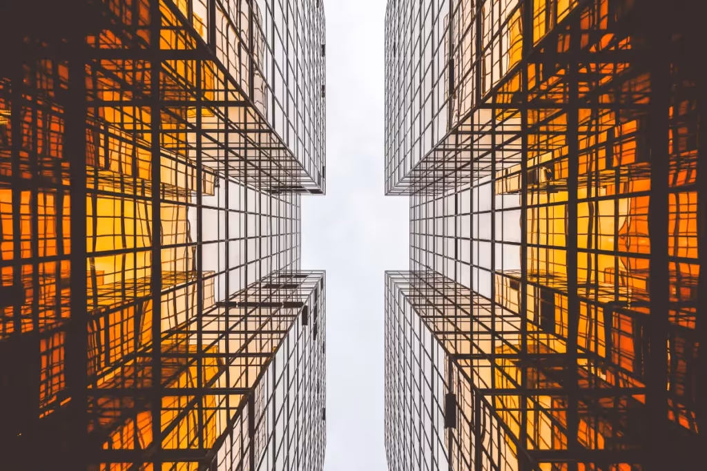 A symmetrical architectural photograph showcasing modern urban towers with reflective golden windows converging toward the sky.