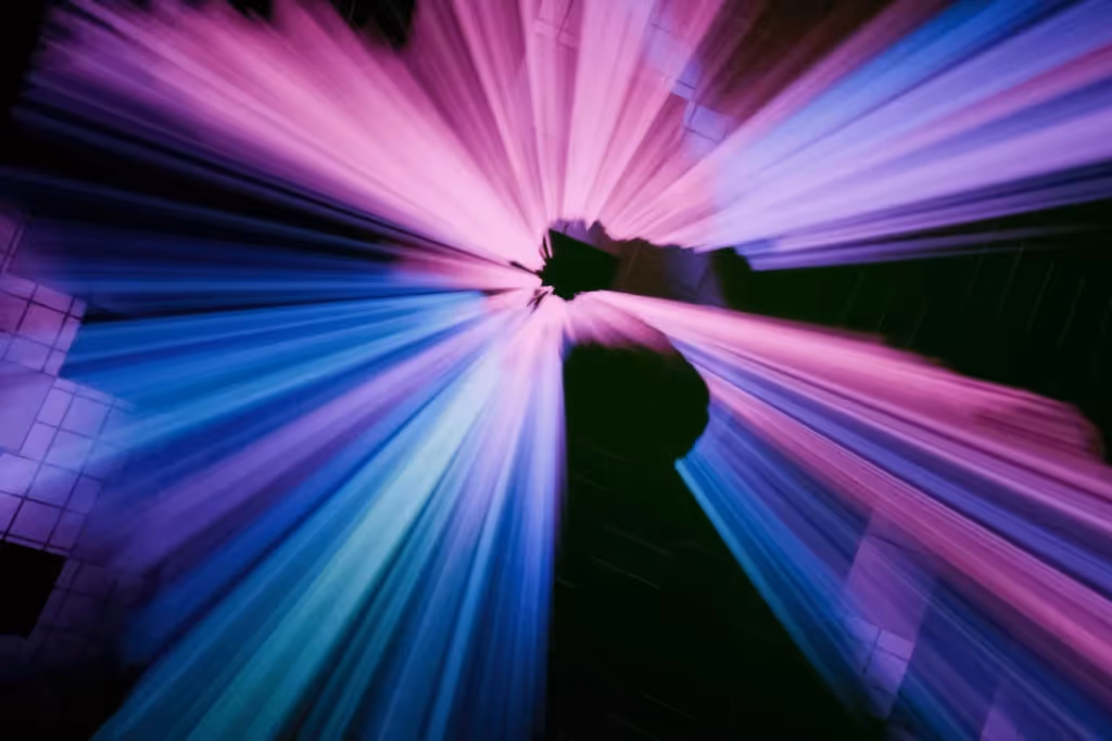 Colorful light rays radiating from a central point, with a smooth transition between purple and blue hues.